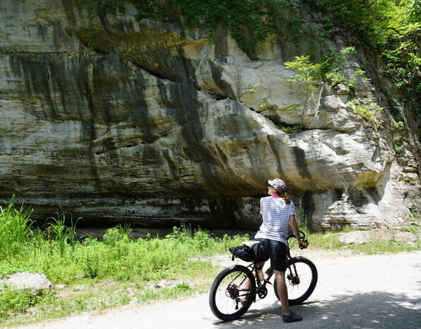 Biker enjoying the huge rock cliffs on Katy Trail