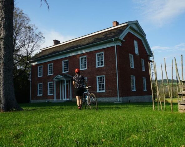 rider approaching an old building on the Empire State Trail